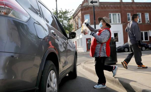 Street vendor Carmen Nava brings an order of tamales to a customer's car while selling her tamales in 4300 block of West Armitage Avenue in Chicago's Hermosa neighborhood on June 19, 2021. At right is her husband Luis Melendez.