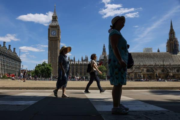 Tourists walk in shade around Parliament Square, in view of the Houses of Parliament, during hot weather in Lo<em></em>ndon in July 2022. | BLOOMBERG