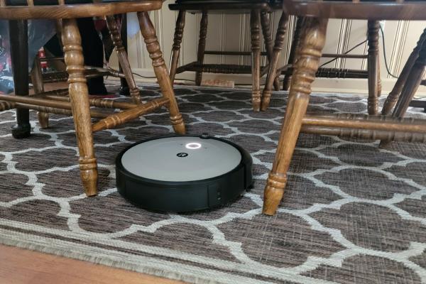 Roomba i1+ Self-Emptying Robot Vacuum on carpet next to chairs
