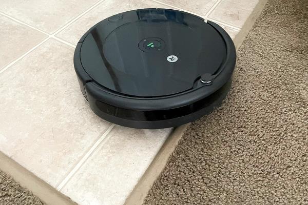 Roomba 694 Robot Vacuum on vinyl flooring navigating toward carpet