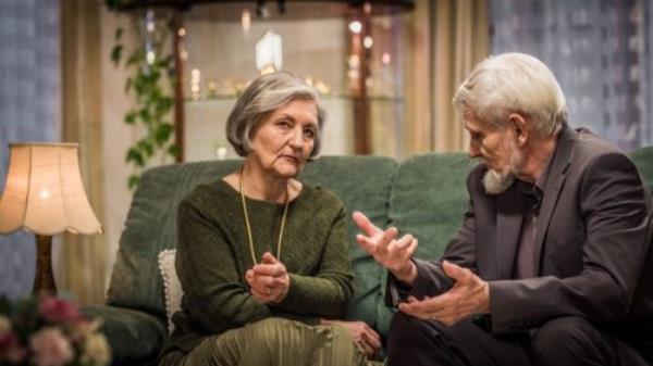 Elderly couple sitting on the living room sofa and havin<em></em>g a serious conversation.