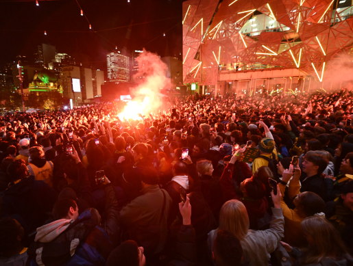 Flares light up crowds at Federation Square.